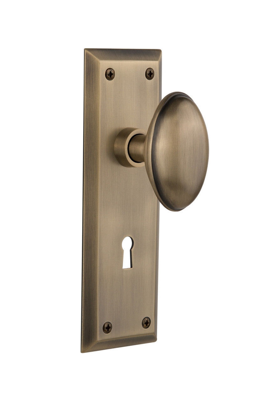 Nostalgic 704587: New York Backplate w/Homestead Knob Passage Door Set - Antique Brass