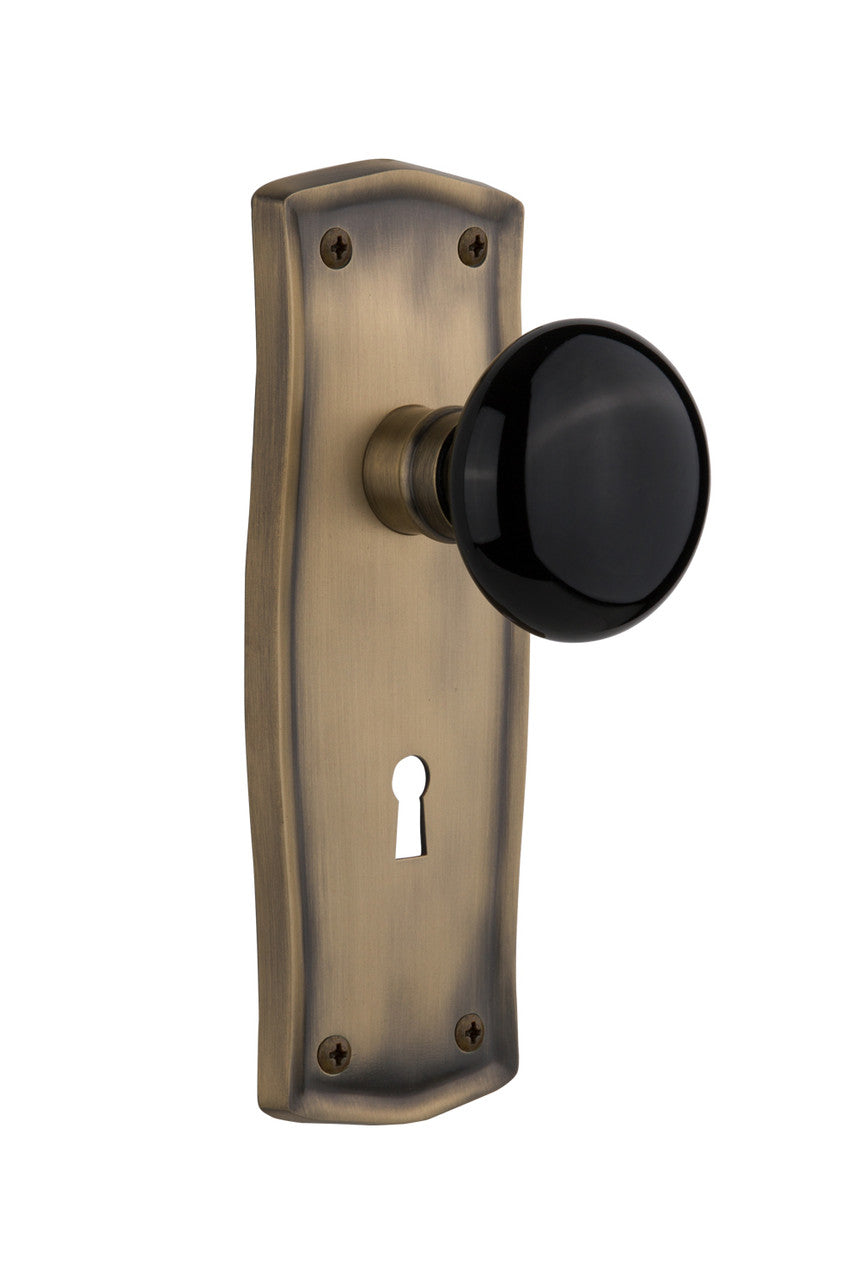 Nostalgic 710082: Prairie Backplate w/Black Porcelain Knob Passage Door Set - Antique Brass
