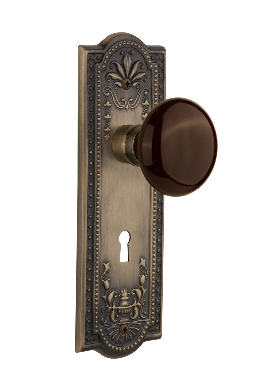 Nostalgic 710508: Meadows Backplate w/Brown Porcelain Knob Passage Door Set - Antique Brass