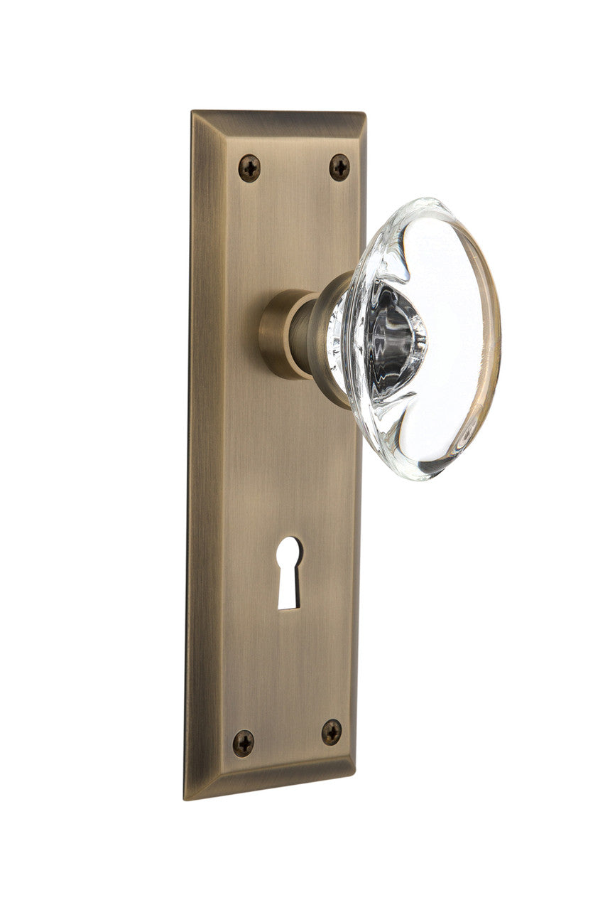 Nostalgic 711395: New York Backplate w/Oval Clear Glass Crystal Knob Passage Door Set - Antique Brass