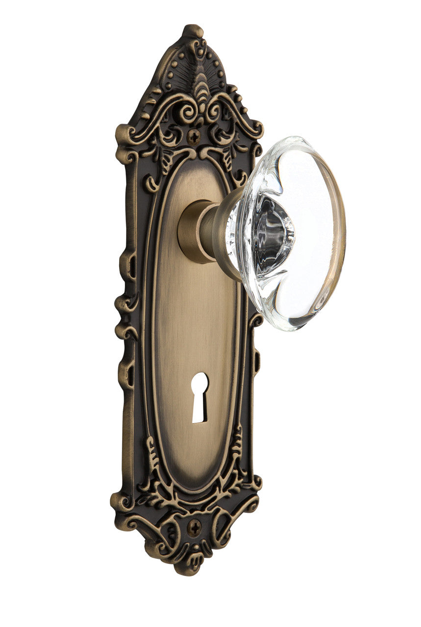 Nostalgic 711409: Victorian Backplate w/Oval Clear Glass Crystal Knob Passage Door Set - Antique Brass
