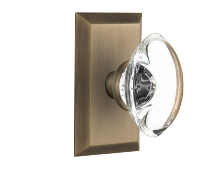 Nostalgic 713338: Studio Backplate w/Oval Clear Glass Crystal Knob Privacy Door Set - Antique Brass