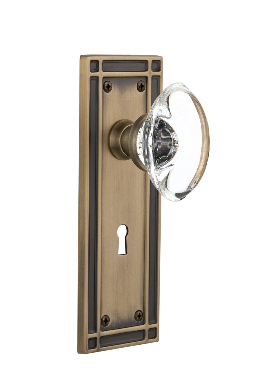 Nostalgic 716294: Mission Backplate w/Oval Clear Glass Crystal Knob Privacy Door Set - Antique Brass