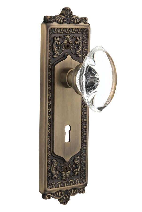Nostalgic 711669: Egg & Dart Backplate w/Oval Clear Glass Crystal Knob Privacy Door Set - Antique Brass
