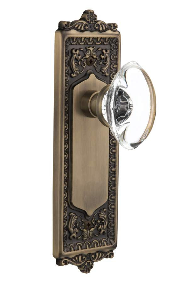 Nostalgic 711423: Egg & Dart Backplate w/Oval Clear Glass Crystal Knob Single Dummy Door Set - Antique Brass