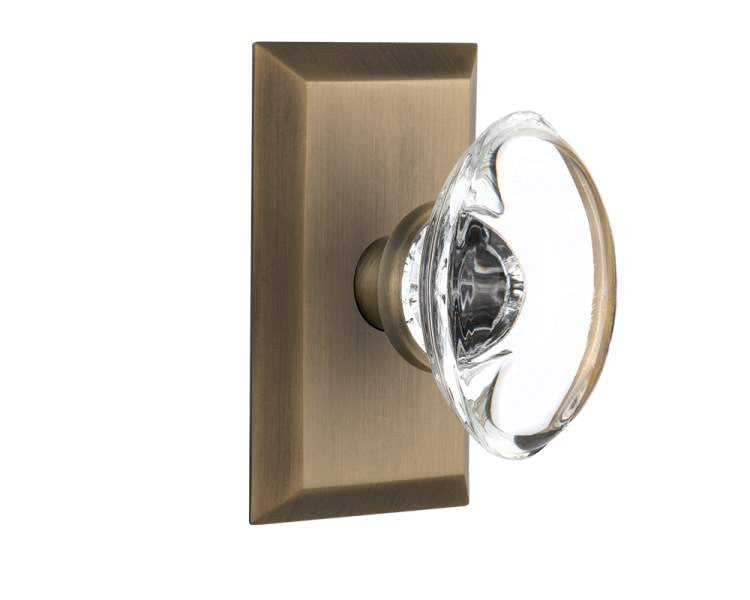 Nostalgic 713242: Studio Backplate w/Oval Clear Glass Crystal Knob Passage Door Set - Antique Brass